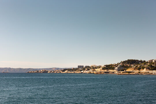 Vue sur le bord de mer de la ville de Marseille, mer au premier plan, ville ensoleill&eacute;e et grand ciel bleu, rade de Marseille