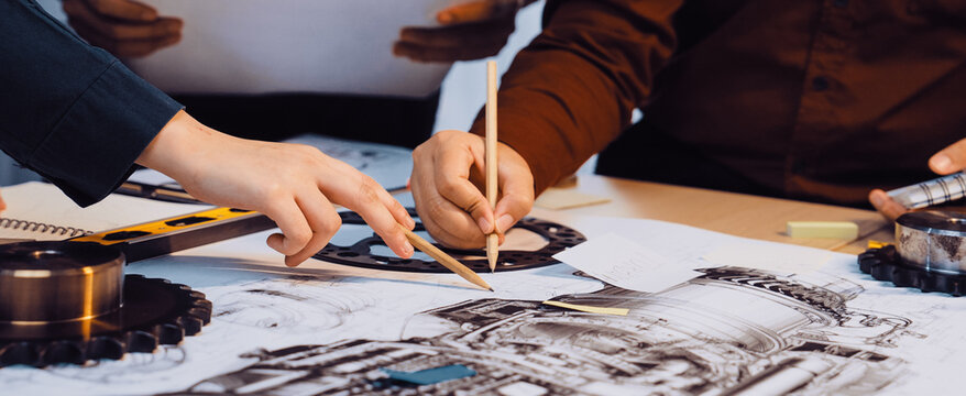 A group of engineers engages in a collaborative process, examining detailed technical drawings and using various tools in a bright and efficient workspace setting. SACTR