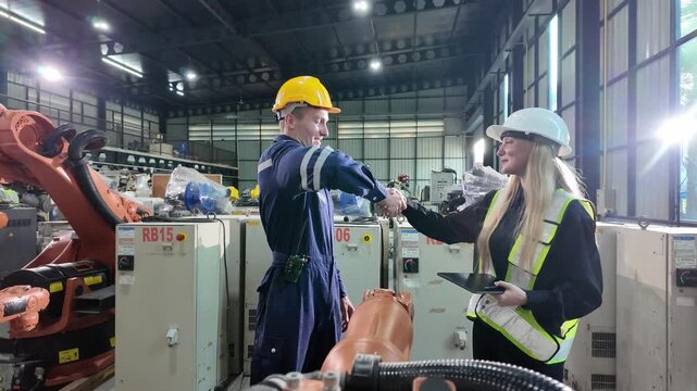 Worker in safety gear overseeing robotic assembly line in modern manufacturing facility