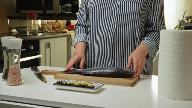 Female hands preparing the sea bass fish for cooking at home kitchen. Concepts of healthy eating and seafood