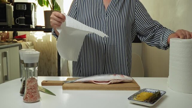 Female hands preparing the sea bass fish for cooking at home kitchen. Concepts of healthy eating and seafood