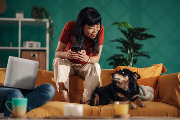 Woman showing smartphone to dog while working from home