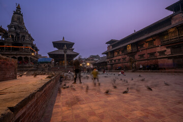 Magic view of Patan Durbar Square in Kathmandu, Nepal. Traditional Newari architecture with illuminated temples and purple sky. Historical UNESCO World heritage with cultural and architectural beauty.
