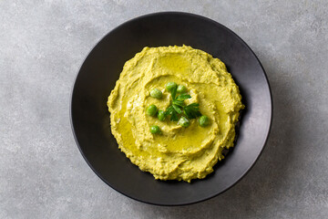 Bowl with tasty green pea hummus, green pea paste, lime and garlic