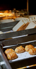 Freshly baked croissants and bread displayed on bakery shelf, warm lighting, inviting ambience, pastry, gourmet, bakery, breakfast. Vertical