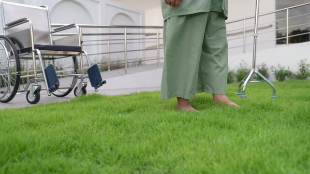 Elderly Person with Wheelchair and Cane on Grass: An elderly person, possibly a senior citizen, stands on a grassy area next to a wheelchair and a quad cane.