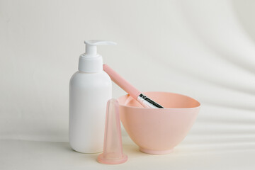 Cosmetologist preparing cosmetic products with bowl, brush, dispenser and cupping therapy device