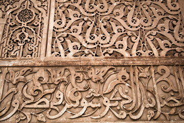 Intricate Moroccan Wall Carving - A detailed close-up of a decorative wall with intricate geometric and calligraphic patterns in Morocco.