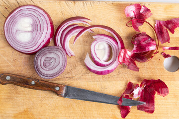 Sliced red onion on wooden cutting board with knife.