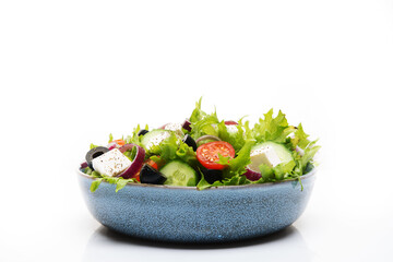 Isolated alad bowl with olives, tomatoes and cucumbers on white background.