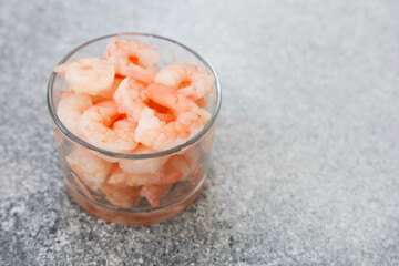 Freshly cooked shrimp served in a clear glass bowl on a textured surface