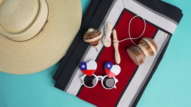 Traditional chilean huaso hat, spinning top, emboque, chilean flag sunglasses, and poncho displayed on a vibrant turquoise background