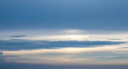 Obraz premium A vast expanse of the sky is filled with dramatic clouds, illuminated by the soft glow of the setting or rising sun