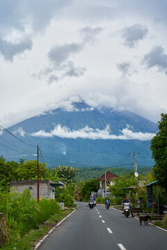 View of the volcano from the road decorated for the holiday in the village. Bamboo decorations along the road. A panorama of Mount Agung covered in clouds.