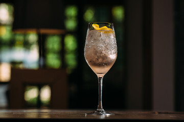 Refreshing pink cocktail garnished with lemon zest on bar counter