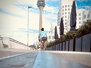 Cyclist on Rhine promenade with Rheinturm tower and Gehry buildings in Düsseldorf, Germany.