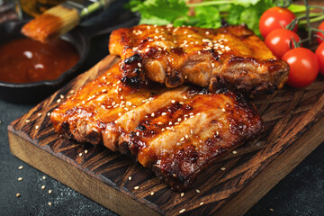 Spicy hot grilled spare ribs from a summer BBQ served with a hot chili pepper and fresh tomatoes