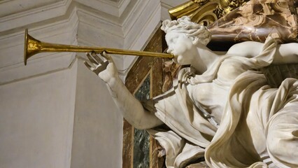Rome, Italy - 10 January 2025. Marble statue of a female figure with robes blowing a golden trumpet inside Chiesa di Sant’Ignazio. © Michael