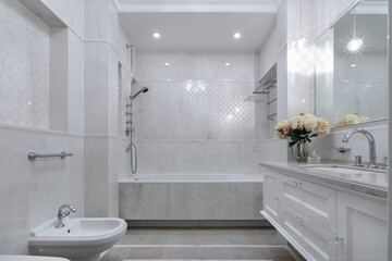 Stylish bathroom design, decorated with white marble tiles and modern accessories.