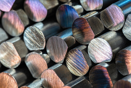 Close-up of cut non-ferrous metal rods stacked together, showing texture and reflections, industrial macro detail