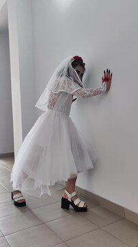 A girl in a white dress and a veil, the image of a scary bride, a zombie,walks around the house, on Halloween