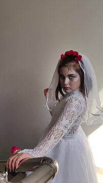A girl in a white dress and a veil, the image of a scary bride, a zombie,walks around the house, on Halloween