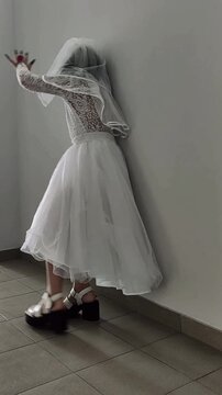A girl in a white dress and a veil, the image of a scary bride, a zombie,walks around the house, on Halloween