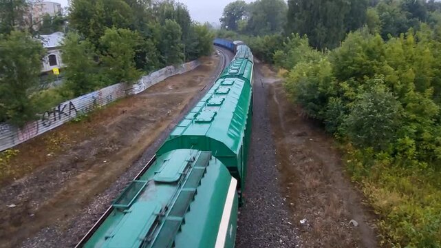 On a summer cloudy day, hopper freight cars transport cargo by rail