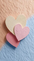 Obraz premium Three colorful paper hearts on a textured background