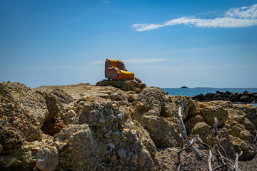 Orange sofa on the rocks by the sea in Corfu Greece