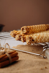 Crispy homemade waffle rolls with nut filling on cooling rack, rustic background