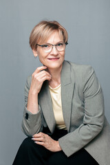 Portrait of happy woman. Confident, successful mature woman on light gray background. Looking at camera. High quality photo