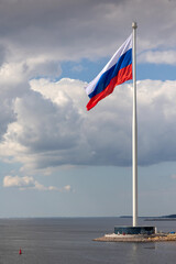 Flag of Russian Federation is flying in air on blue sky and white cumulus clouds. National flag of Russian. vertical photo.