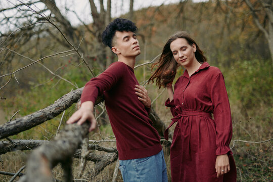 A genuine couple share a quiet, natural moment outdoors, posing with relaxed expressions and subtle movement that convey sincere connection and credible human emotion in a rustic setting.