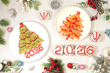 Christmas and New Year dishes. Curd muffins with pomegranates in glaze with numbers 2026 and a Christmas tree made of kiwi and tangerines for a festive table, an idea for decorating food