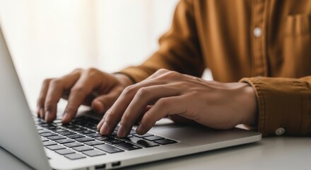 Young male typing on laptop in casual outfit