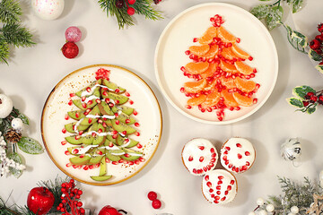 Christmas and New Year dishes. Edible Christmas trees made of tangerines, kiwi and pomegranate for a festive table, an idea for decorating food and decorating New Year dishes for children