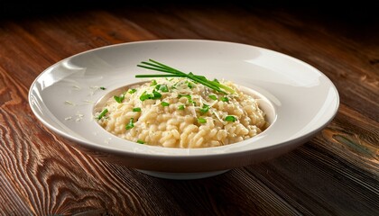 delicious creamy risotto with parmesan and fresh chives in a white bowl on a wood background