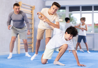 Two boys learn to do painful hand grip in self-defense lesson in modern sports gym