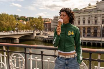 Young woman enjoying ice cream on a bridge in bilbao