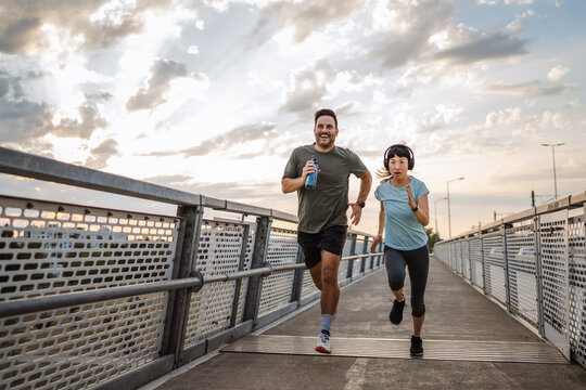 Couple running on bridge at sunset, promoting healthy lifestyle