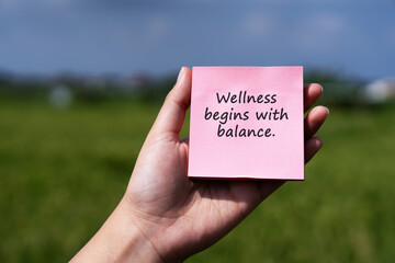 Hand holding a pink sticky note with motivational text 