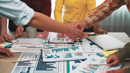 A group of professionals engaged in a collaborative discussion while analyzing business analytics reports and data visualizations in a modern office space. SACTR - Powered by Adobe