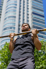 Young athlete performing pull-ups on outdoor gym bars