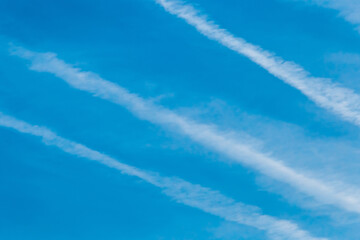 Traces of an airplane against a blue sky with clouds, background