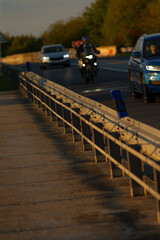 A man on a motorcycle is riding steadily down the long stretch of a highway, enjoying the freedom of the open road during the evening hours