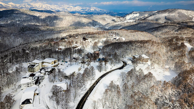 Fototapeta Winding road through a remote snowy mountain village on a sunny winter day