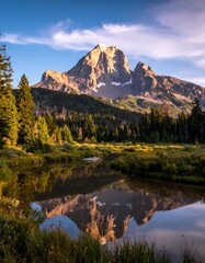 Obraz premium A majestic mountain peak, reflected serenely in a tranquil alpine lake, bathed in the golden hues of dawn.