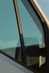 This image offers a closeup of a vehicles side mirror and windshield, highlighting reflections and surroundings to showcase the blend of aesthetics and functionality in modern design