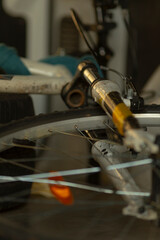 A detailed closeup image of a bicycle wheel, prominently displaying the brake caliper alongside the spokes, all set within a workshop environment filled with various tools and equipment